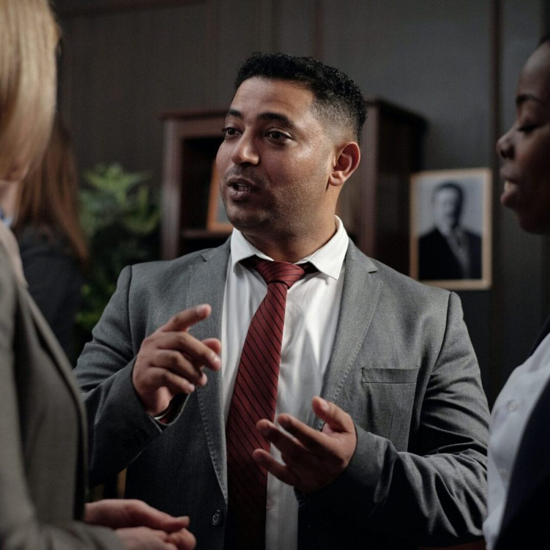 A man in a suit talking to two other people.